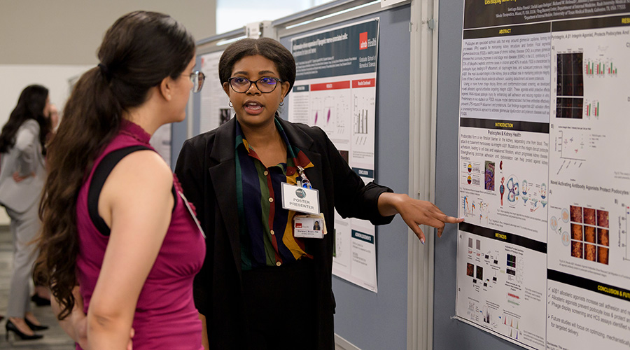 A woman pointing the a informational board and speaking to another woman