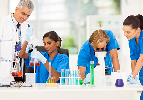 Team of researchers in a laboratory conducting experiments with test tubes, glassware, and a microscope.